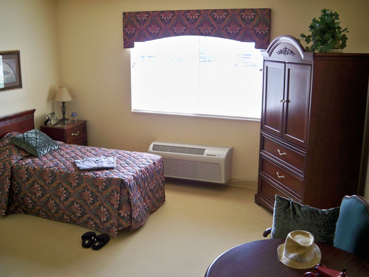 A cozy bedroom with a single bed, dresser, and a lamp by the window.