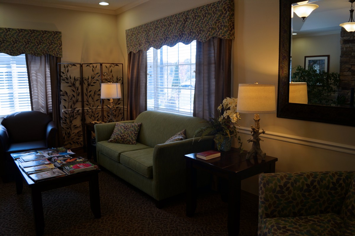A cozy living room featuring a green sofa, lamps, and elegant decor.