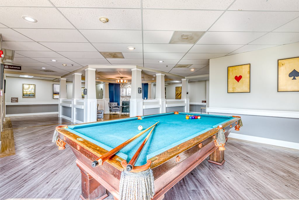 A spacious recreation room featuring a billiards table with cues and balls neatly arranged.