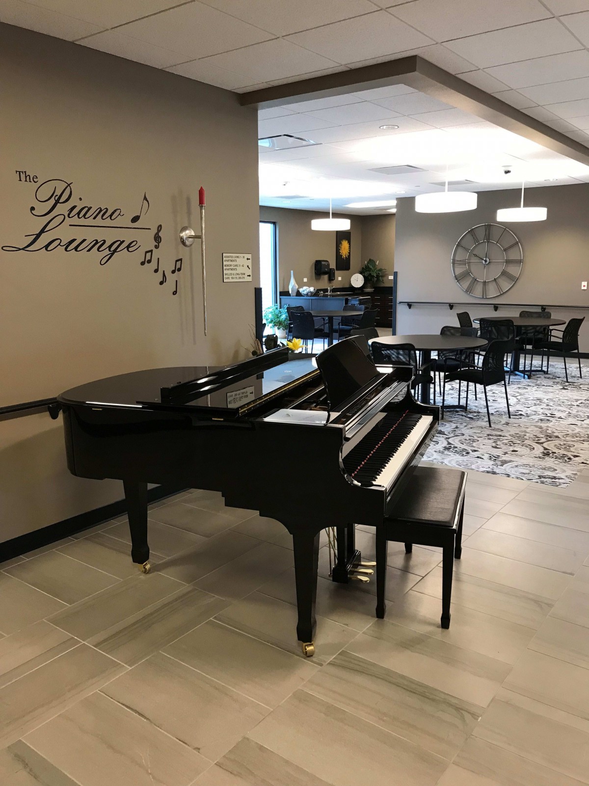 A grand piano in a cozy lounge area, surrounded by soft lighting and modern decor.