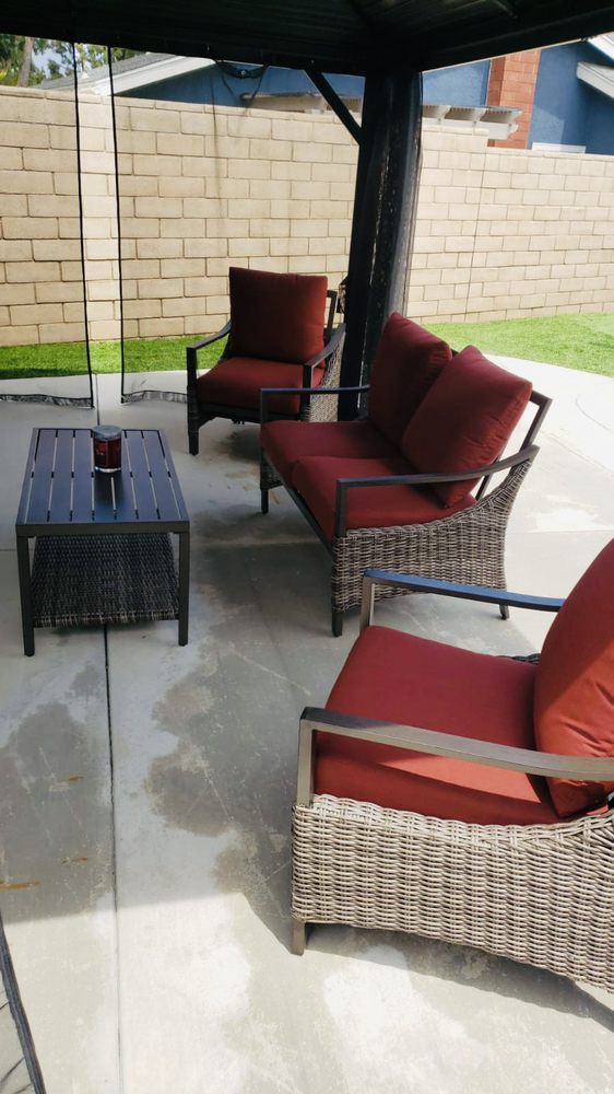 Outdoor patio furniture set with red cushions on a concrete surface.