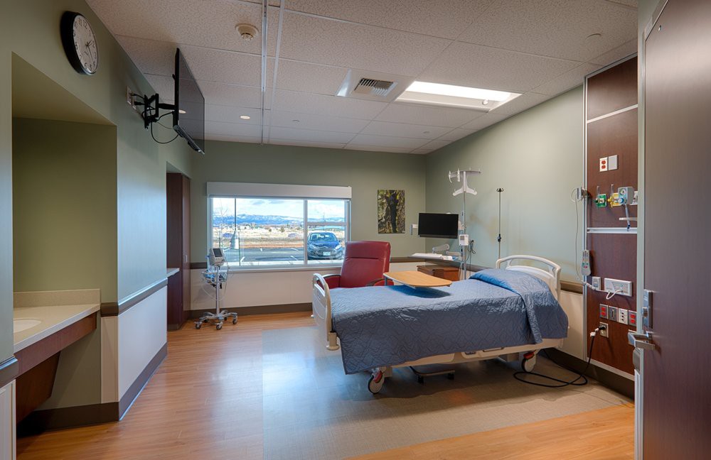 A clean and modern hospital room with a bed and medical equipment.