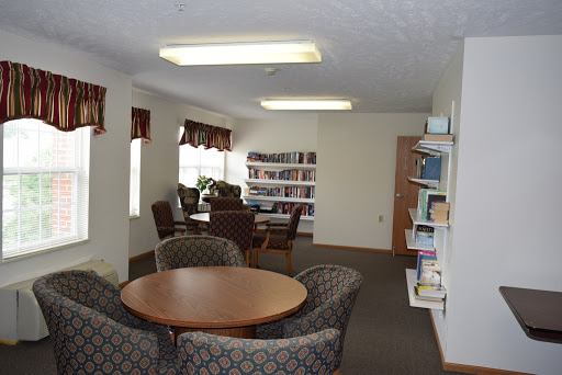 A cozy reading area featuring plush chairs, a circular table, and shelves filled with books.
