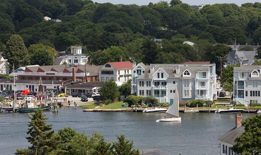 A scenic waterfront view featuring sailboats and charming houses along the coast.