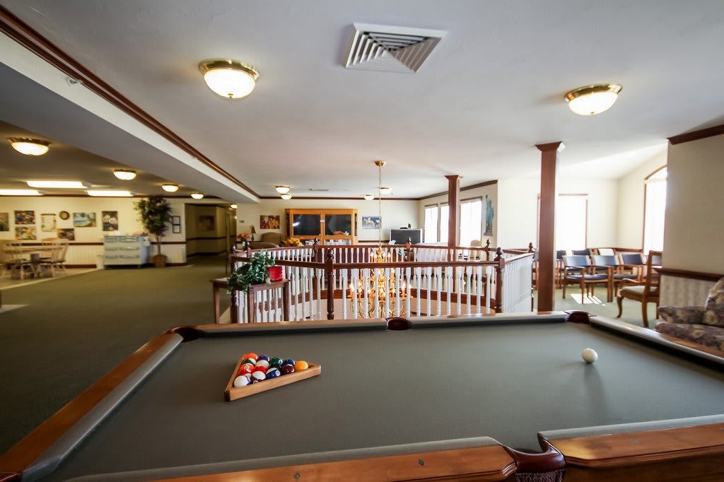 A well-lit game room featuring a pool table with balls racked and ready for play.