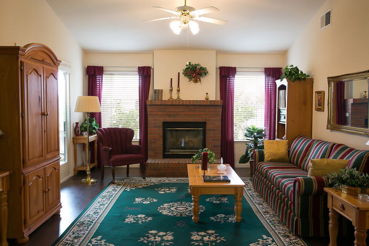 A cozy living room with a central fireplace, surrounded by comfortable furniture and warm decor.