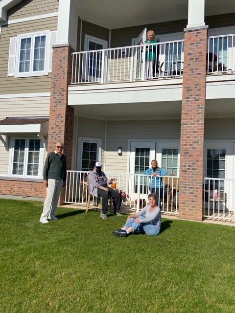 A group of people enjoying a sunny day outside a residential building with balconies.