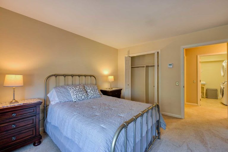 A cozy bedroom with a metal bed frame, bedside lamp, and an open closet.