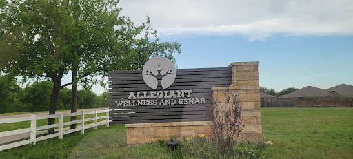 A sign for Allegiant Wellness and Rehab, surrounded by greenery.