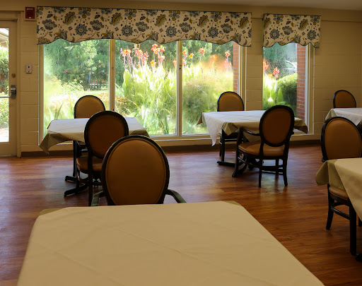 A serene dining area featuring tables and chairs with large windows allowing natural light to fill the space.