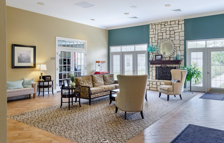 A spacious and elegantly decorated living room featuring comfortable seating, a central fireplace, and abundant natural light.