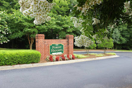 Entrance to a residential area with a brick sign and landscaped surroundings.