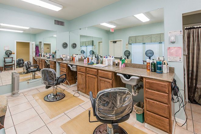 An empty hair salon with styling chairs and mirrors lined up along the counter.