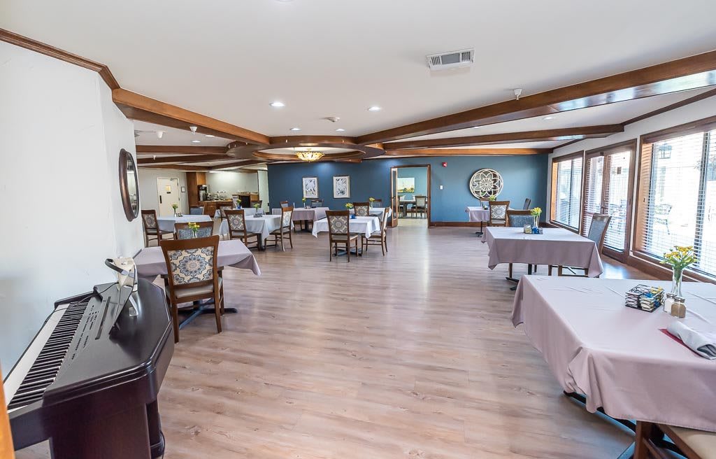 A spacious restaurant dining area with wooden floors, neatly arranged tables and chairs.