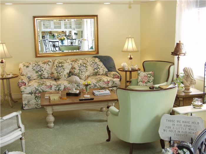A cozy living room with a floral-patterned sofa, armchair, and decorative mirror.