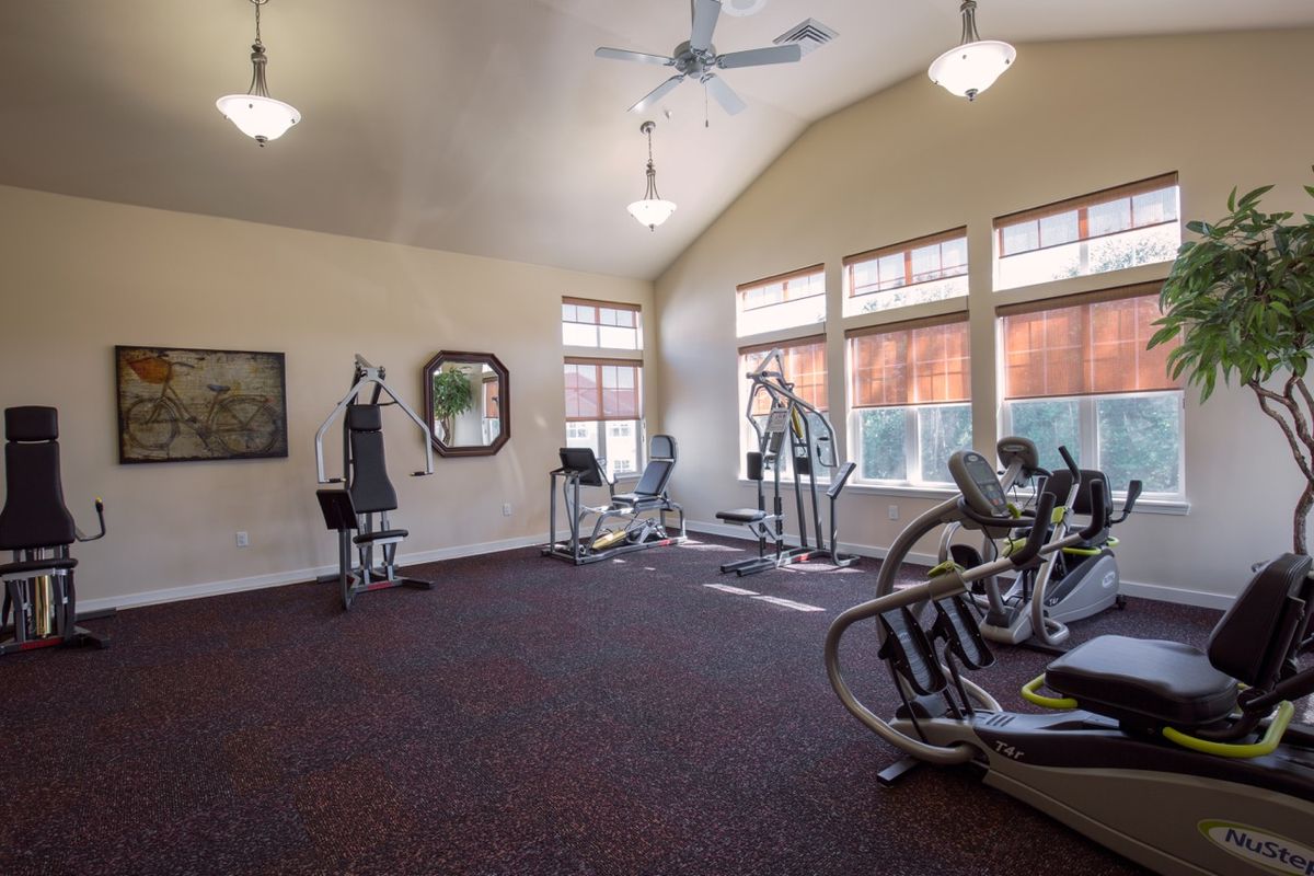 A well-lit gym with various exercise equipment including cardio machines.