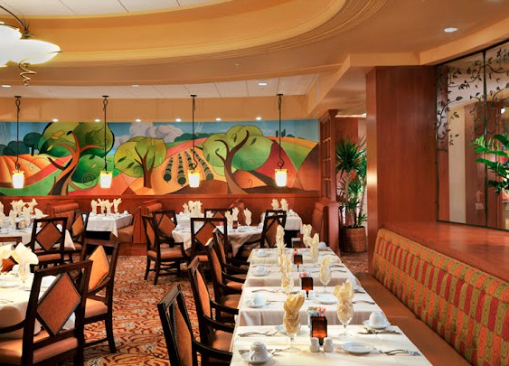 A beautifully decorated restaurant dining room with neatly set tables and eye-catching artwork on the wall.