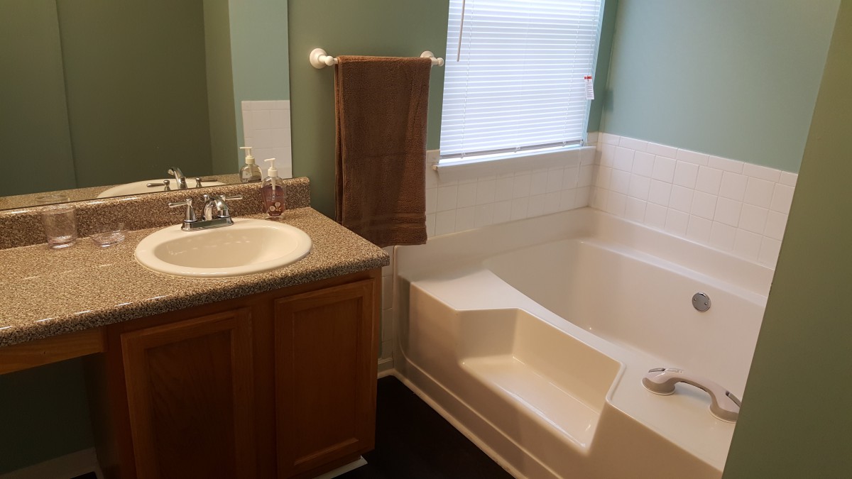A bathroom featuring a sink with a towel and a bathtub near a window.