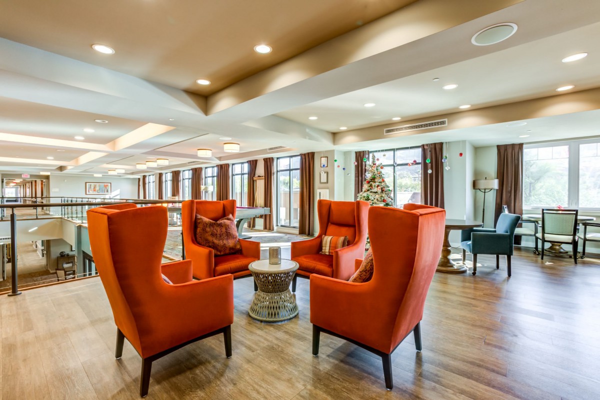A modern lounge area with orange armchairs and abundant natural light.