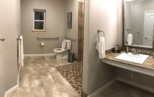 A modern, spacious bathroom featuring a toilet and vanity area with neutral tones.