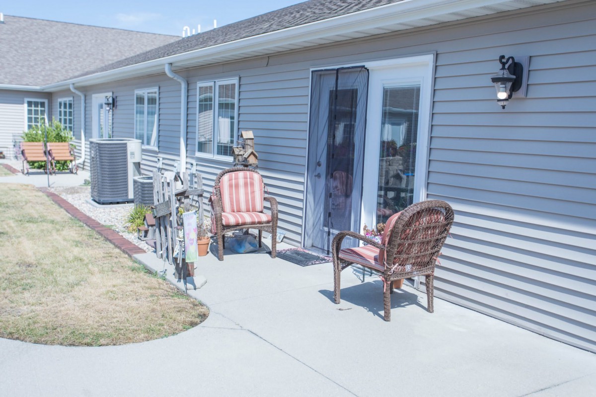 A cozy outdoor patio with two chairs in front of a house.