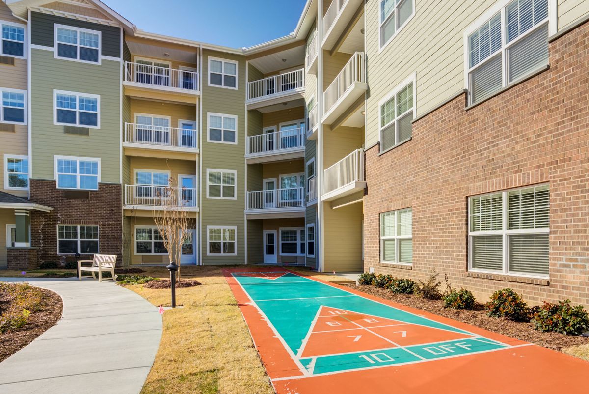 A modern apartment building with a courtyard featuring a shuffleboard court.