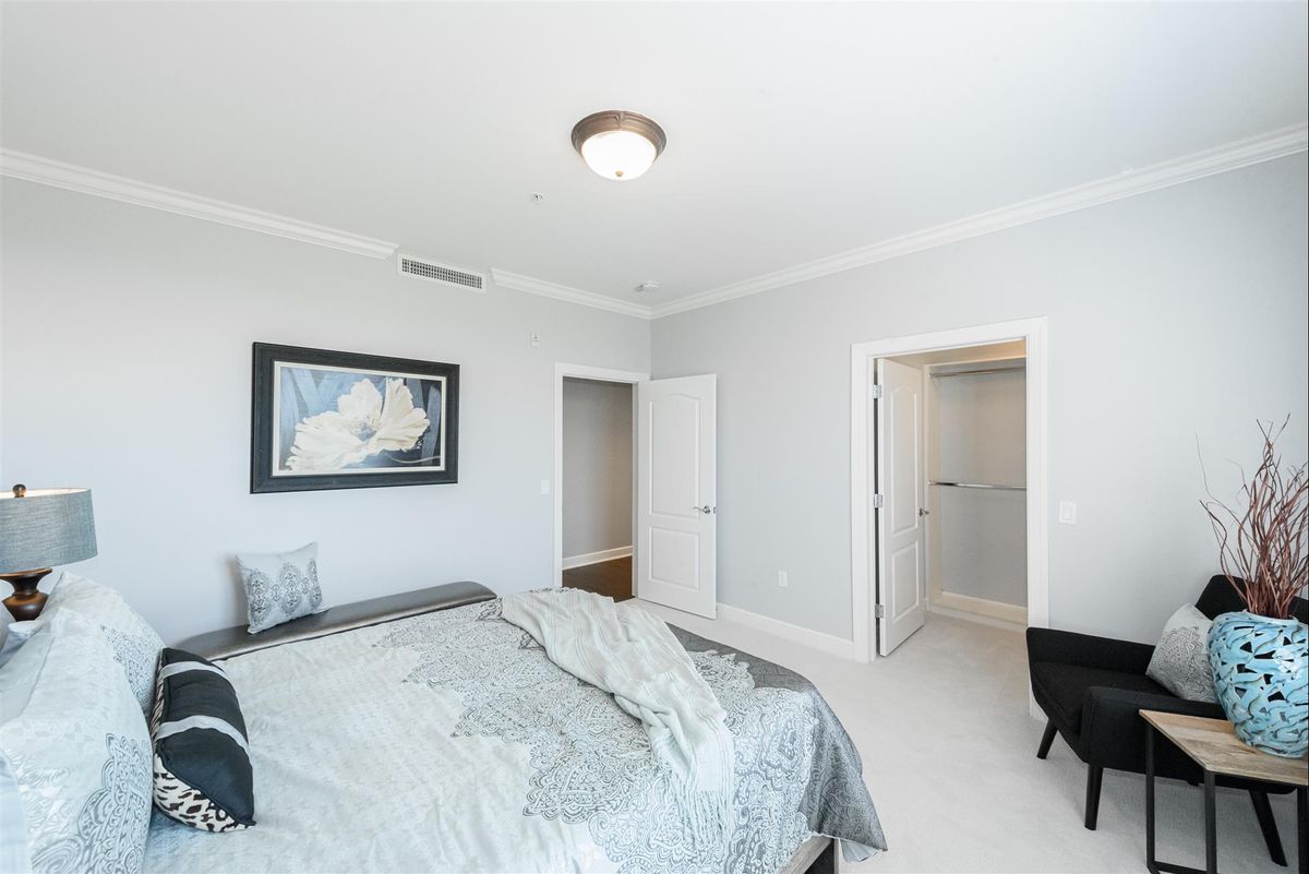 A modern bedroom featuring a neatly made bed, contemporary decor, and soft lighting.