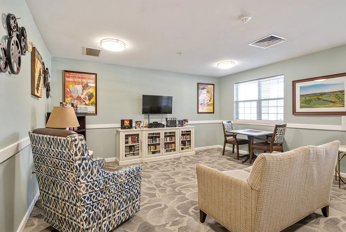 A cozy living room with armchairs, bookshelves, and a television set.