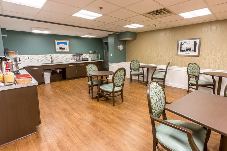 A well-lit dining area with several tables and chairs, featuring wooden flooring and tasteful decor.