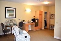 A cozy, carpeted room featuring a chair, sink, and wardrobe.