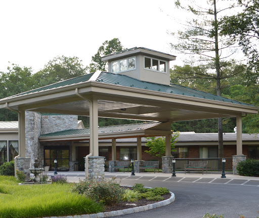 A welcoming entrance to a modern building surrounded by lush greenery.