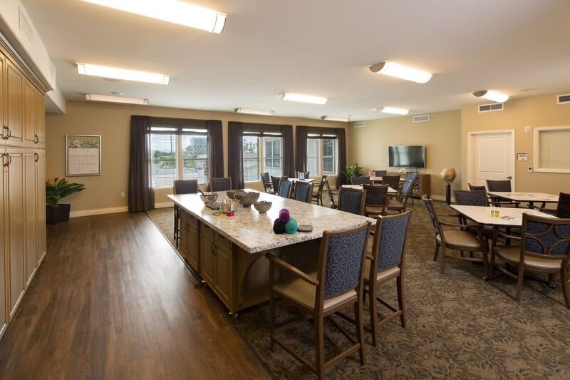A spacious dining area with a kitchen island, surrounded by chairs and large windows.