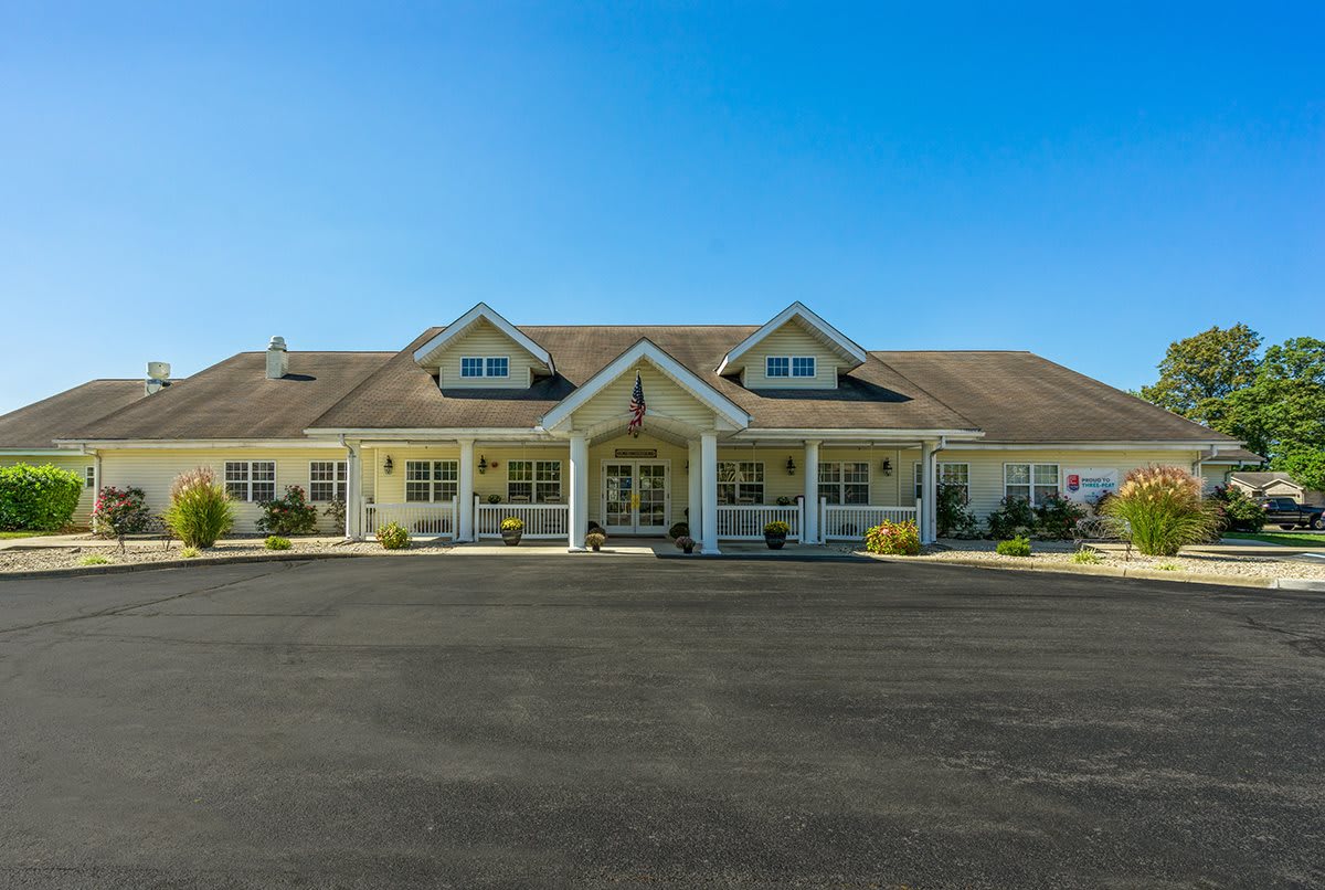 A large residential building with a spacious driveway under a clear blue sky.