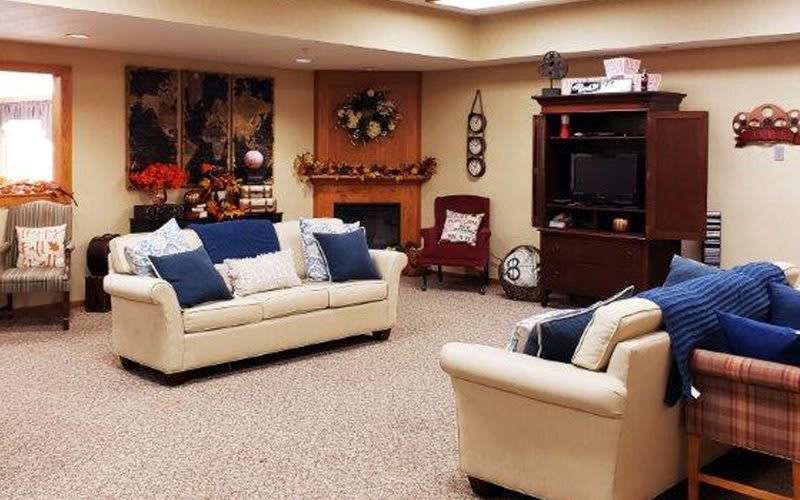 A cozy living room with comfortable sofas, a television, and a fireplace adorned with decorations.