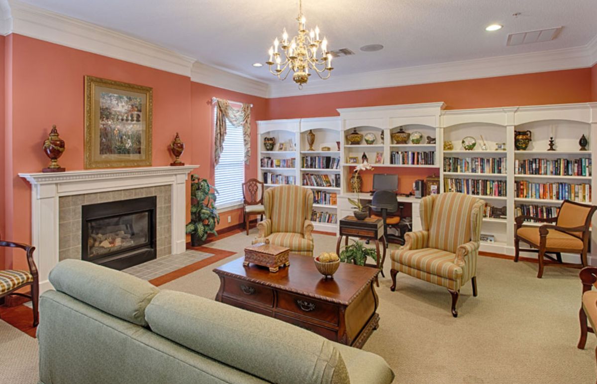 A cozy and elegantly furnished living room featuring bookshelves, a fireplace, and comfortable seating.