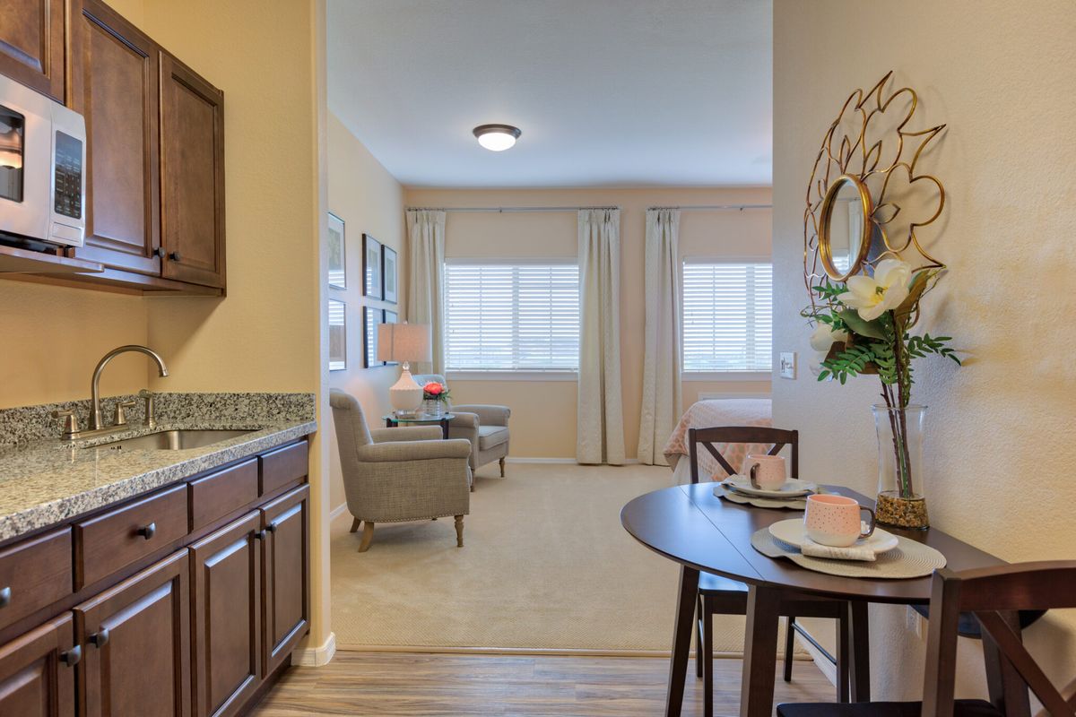 A cozy living space featuring a dining table set, elegant chairs, and large windows allowing natural light to flood the room.