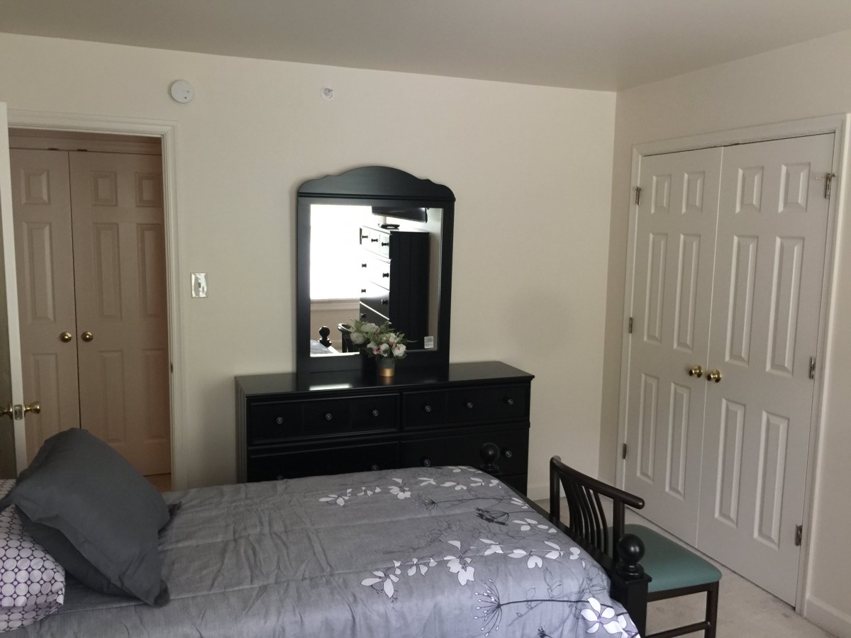 A cozy bedroom featuring a bed, dresser with a mirror, and decorative elements.