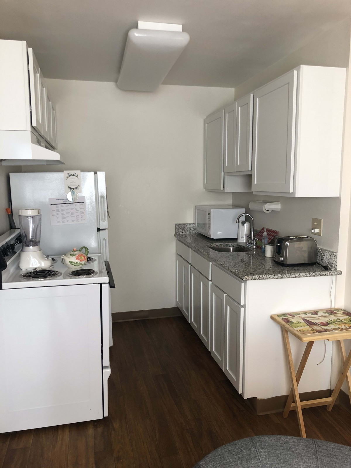 A compact kitchen with white cabinets, a refrigerator, stove, and microwave.