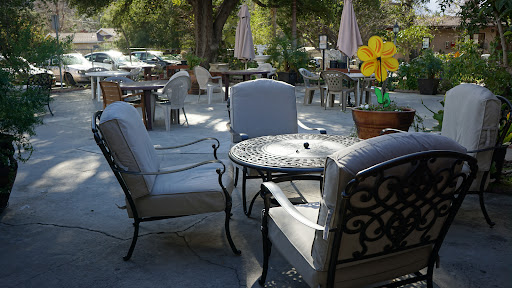 A serene outdoor cafe setting with comfortable seating and vibrant flowers.