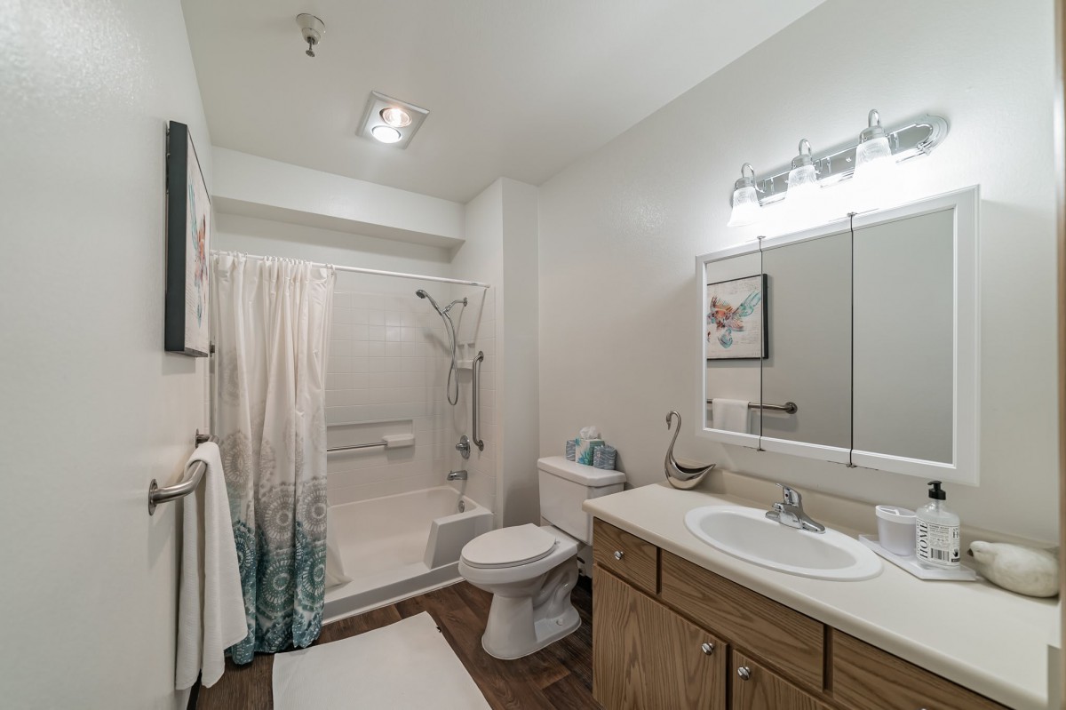 A modern bathroom interior with a shower, sink, toilet, and mirror.