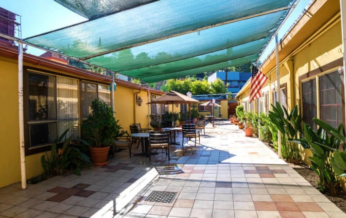 A sunny courtyard with outdoor seating, shaded by green canopies.