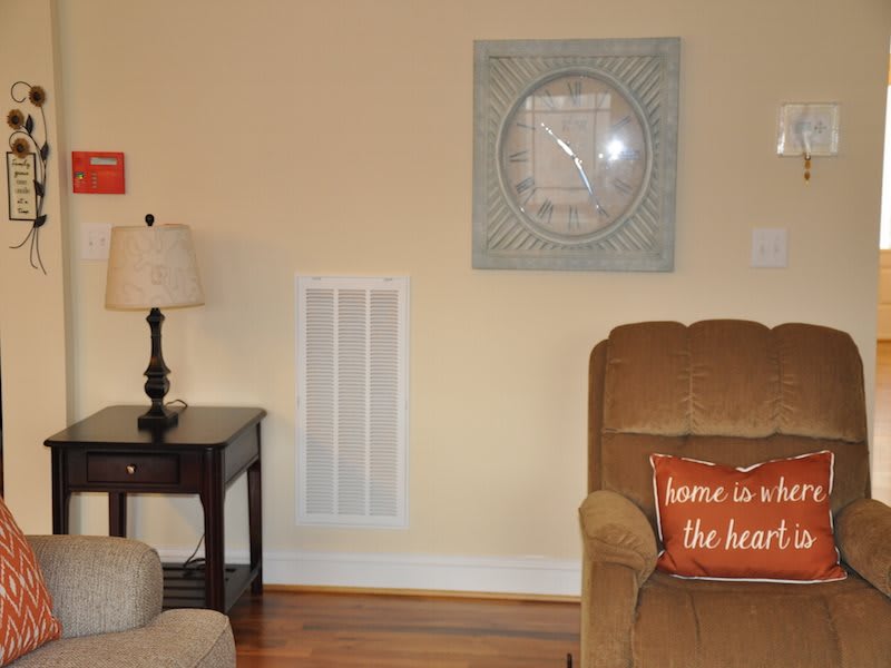 A cozy living room corner with a lamp, artwork, and an armchair.