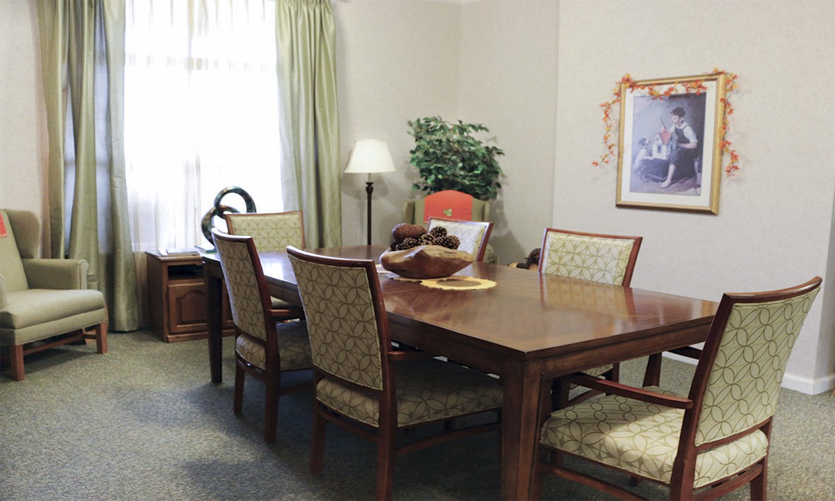 A dining room featuring a wooden table with chairs, a lamp, and decorative elements.