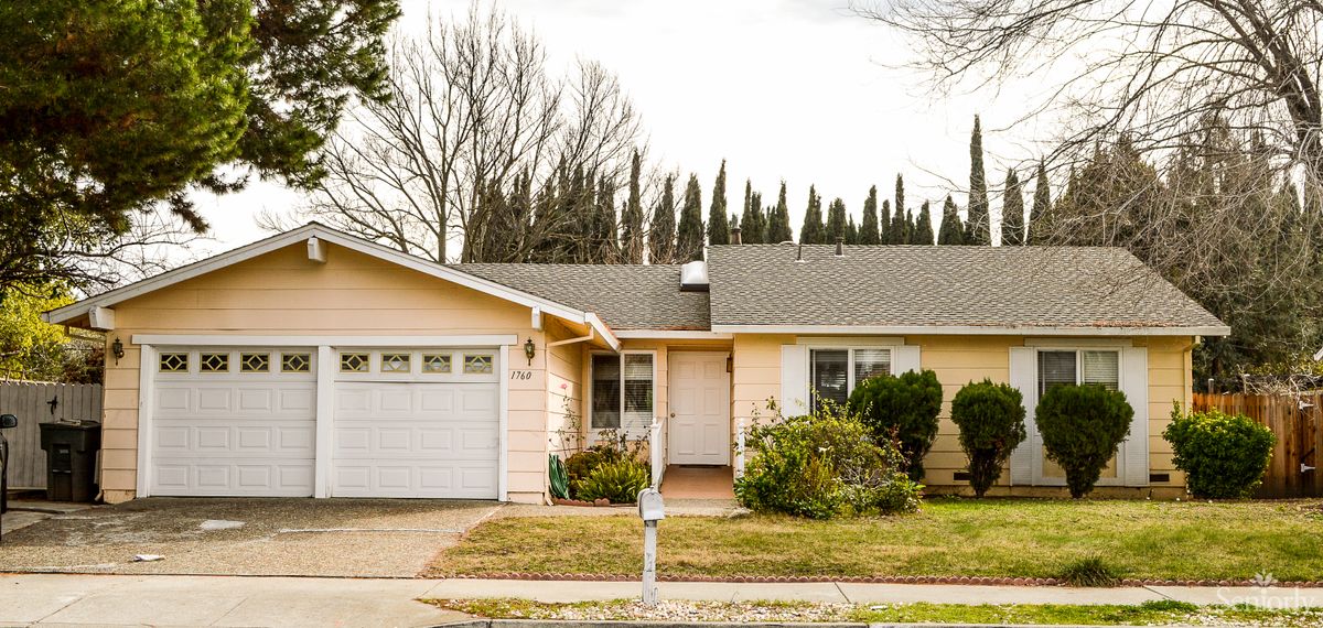 A suburban house with a driveway and a garage, surrounded by trees.