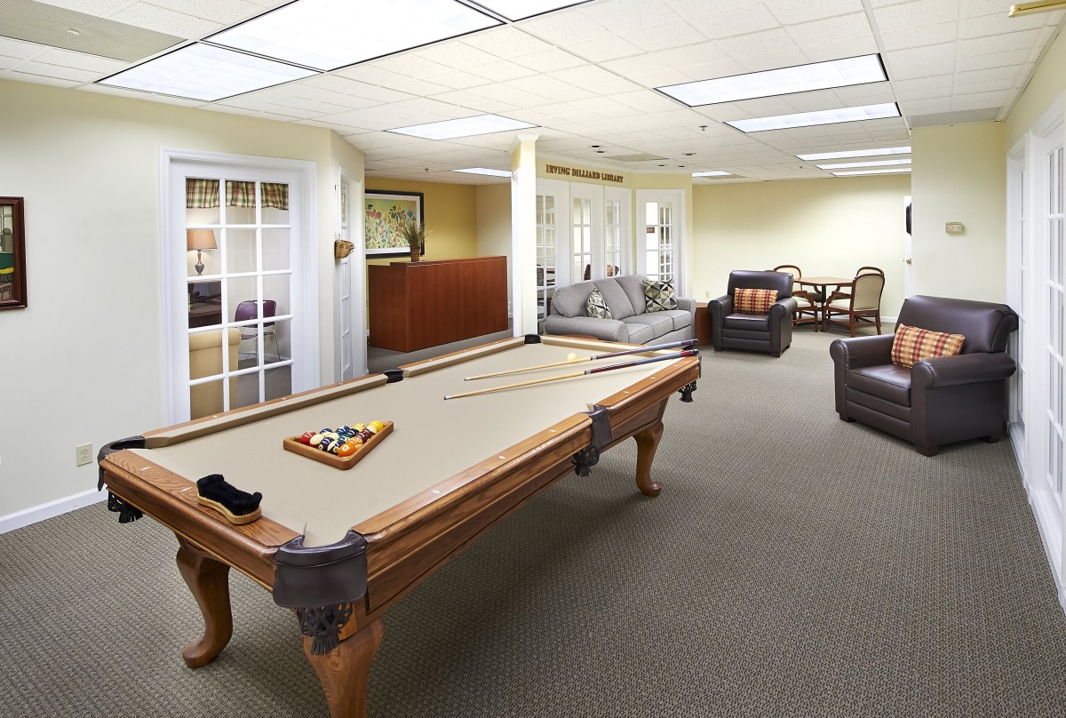 A spacious game room featuring a pool table and comfortable seating.