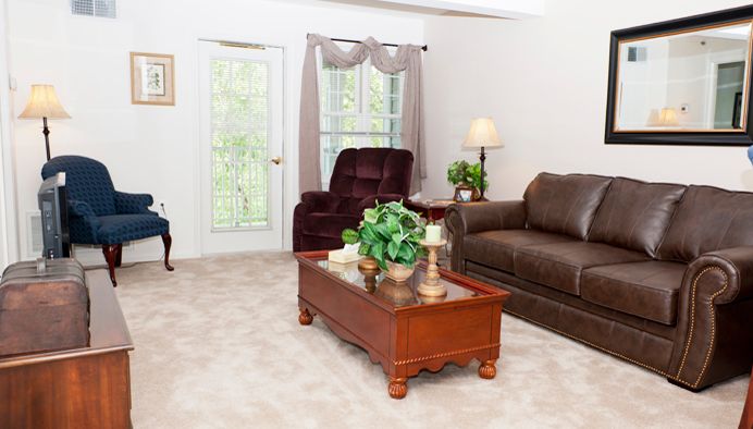 A bright living room with a sofa, armchair, and wooden coffee table.