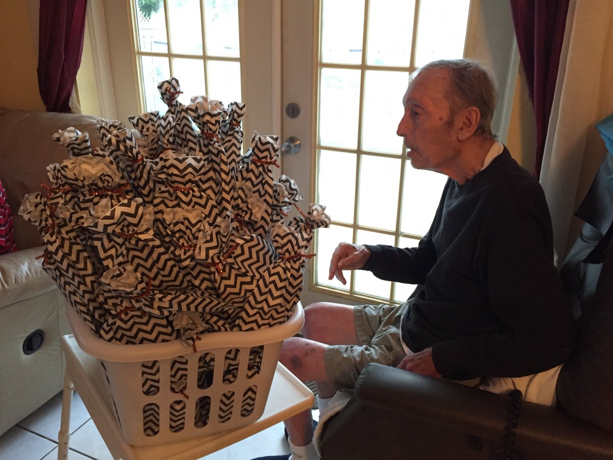 A man sits indoors, looking at a basket filled with patterned items.