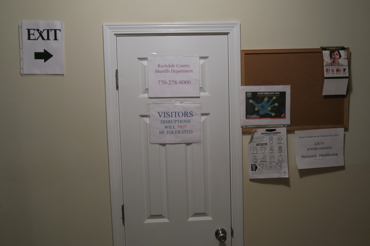 A door with multiple signs directing visitors, adjacent to a bulletin board on the wall.