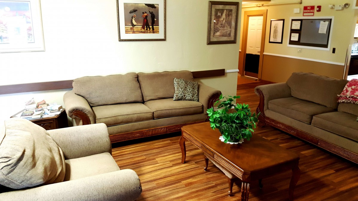 A cozy living room with a sofa set, coffee table, and indoor plants on a wooden floor.