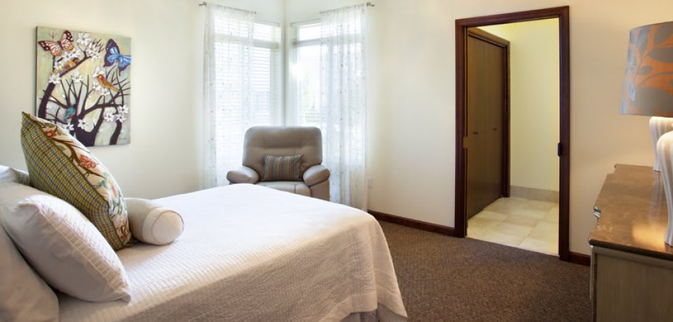 A cozy bedroom with a comfortable chair and natural light streaming through the windows.